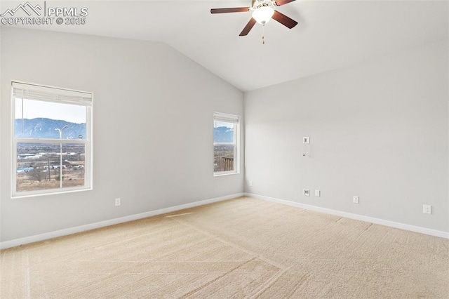 carpeted spare room featuring lofted ceiling, ceiling fan, baseboards, and a mountain view