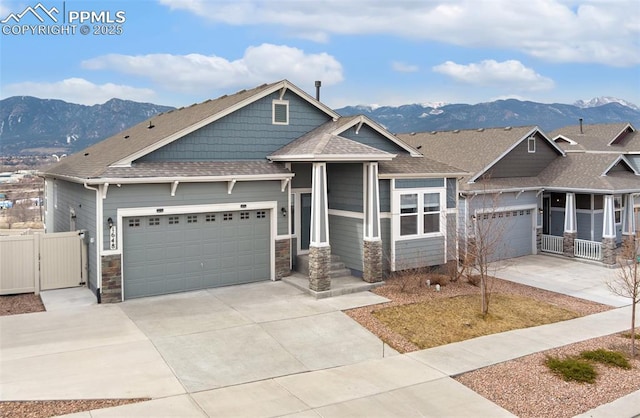 craftsman house featuring a mountain view, a garage, fence, concrete driveway, and roof with shingles