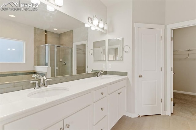 bathroom featuring a stall shower, a spacious closet, and a sink