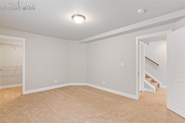 spare room featuring stairs, baseboards, and light colored carpet