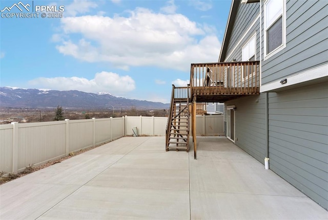 view of patio / terrace with stairs, a deck with mountain view, and a fenced backyard