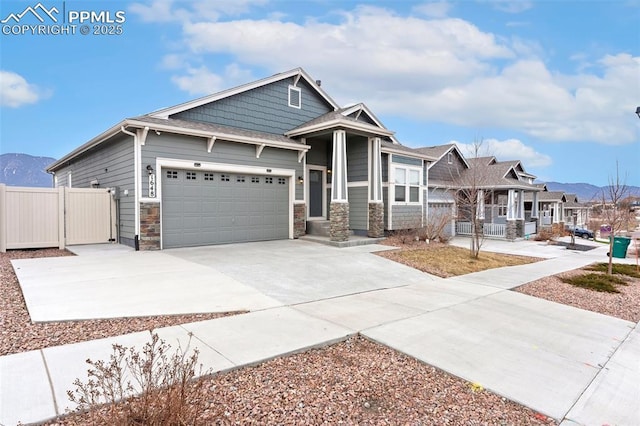 craftsman-style home with concrete driveway, stone siding, a residential view, an attached garage, and fence