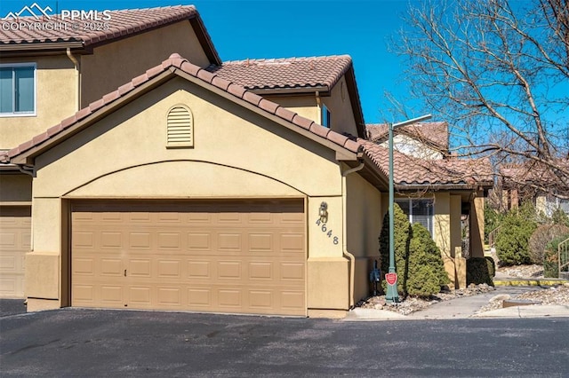 view of front of property featuring driveway, a tile roof, and stucco siding