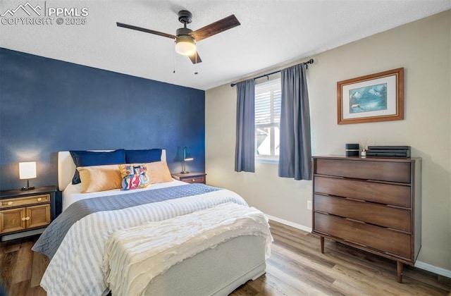 bedroom featuring ceiling fan, a textured ceiling, wood finished floors, and baseboards