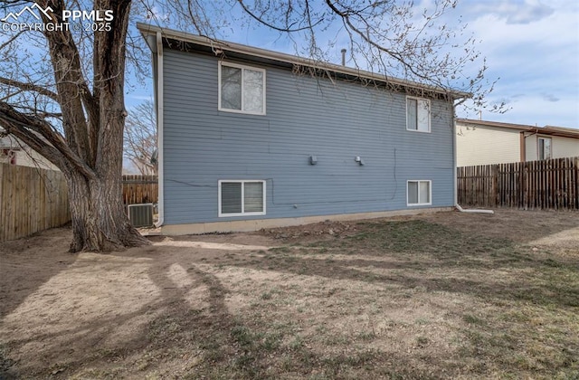 back of house with a fenced backyard and cooling unit