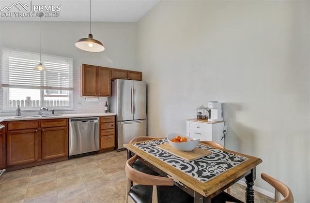 kitchen featuring brown cabinets, stainless steel appliances, light countertops, hanging light fixtures, and a sink