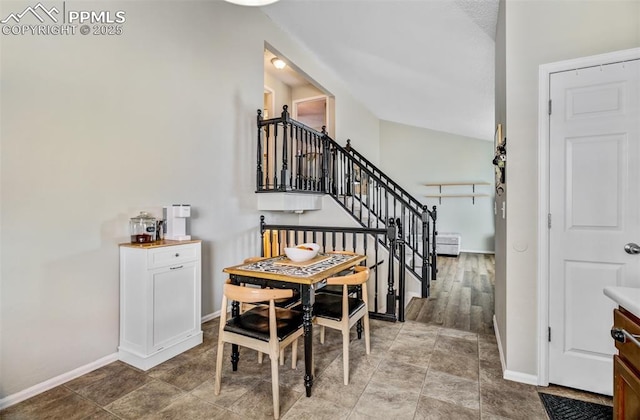 dining room with lofted ceiling, baseboards, and stairs