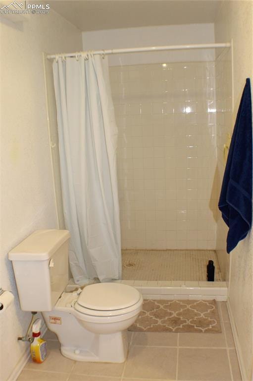 bathroom with tile patterned floors, toilet, and a shower stall