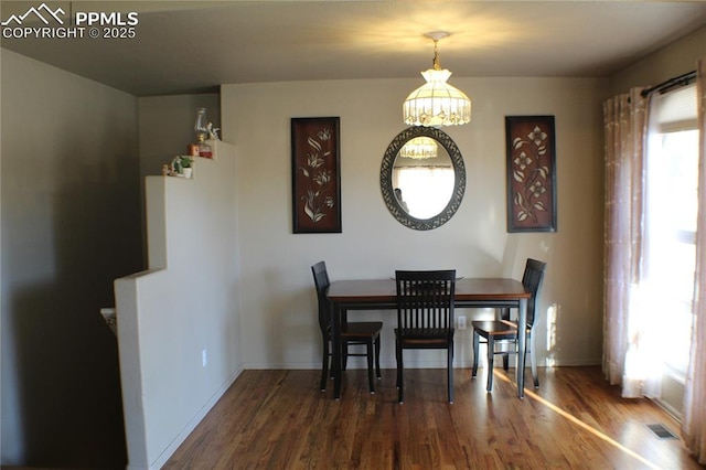 dining room with a chandelier, visible vents, baseboards, and wood finished floors