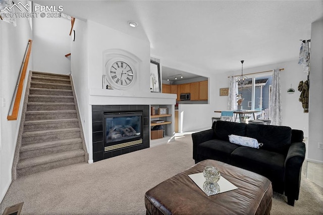 living area with carpet, visible vents, stairway, and a tile fireplace