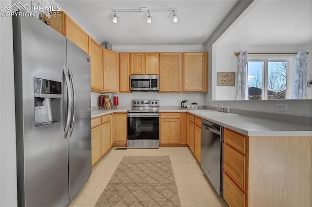 kitchen featuring a peninsula, light brown cabinets, stainless steel appliances, and light countertops