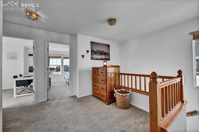 corridor featuring carpet floors, baseboards, and an upstairs landing