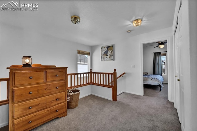 hallway featuring carpet floors, baseboards, and an upstairs landing