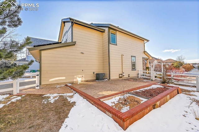 snow covered back of property featuring a patio area, fence, and central air condition unit