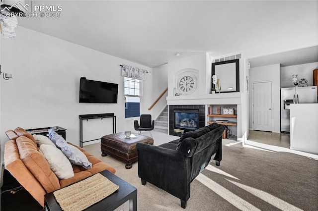 living area with visible vents, a tiled fireplace, and light colored carpet