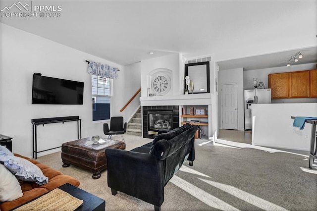 living area featuring track lighting, light colored carpet, visible vents, and a tiled fireplace