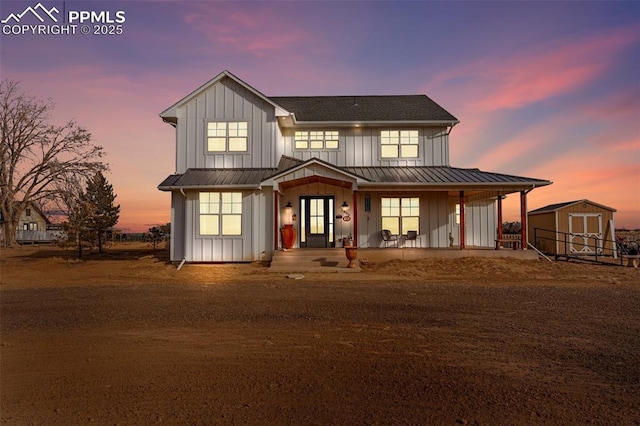 view of front of home with a porch, board and batten siding, a standing seam roof, metal roof, and a shed