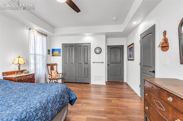 bedroom featuring ceiling fan, wood finished floors, visible vents, baseboards, and a closet