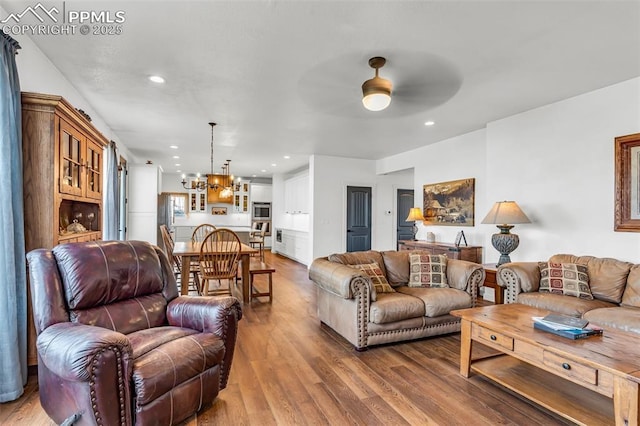 living room with ceiling fan with notable chandelier, recessed lighting, and wood finished floors