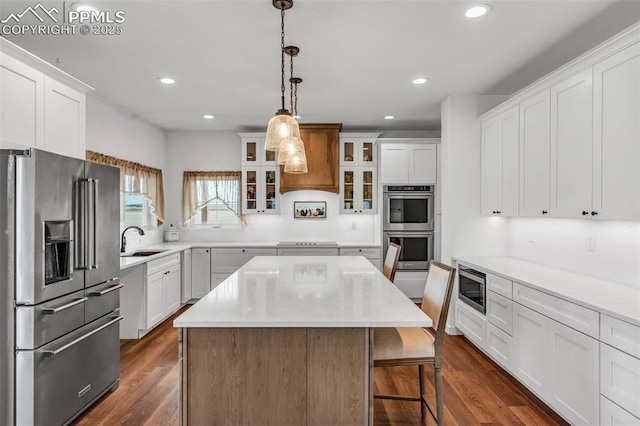 kitchen featuring recessed lighting, stainless steel appliances, a kitchen island, a sink, and dark wood-style floors