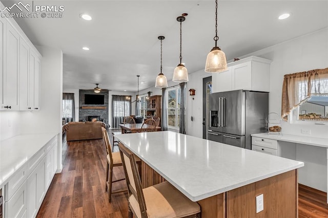 kitchen with dark wood-style flooring, recessed lighting, open floor plan, a stone fireplace, and high end refrigerator