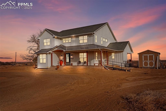 view of front of house featuring covered porch, a shed, board and batten siding, and an outdoor structure