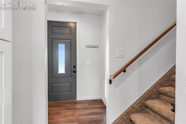 foyer entrance with stairway, dark wood-style flooring, visible vents, and baseboards