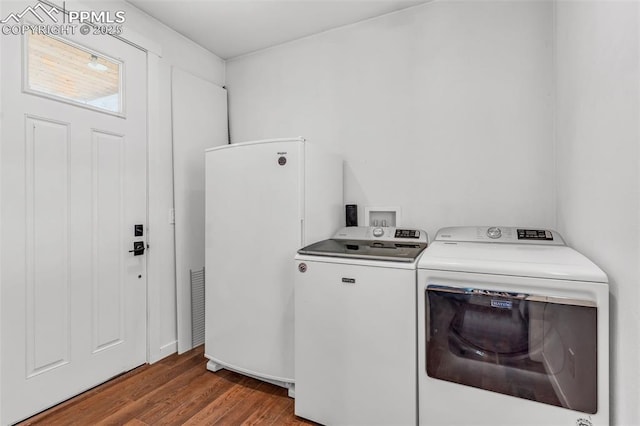 clothes washing area with laundry area, wood finished floors, and washer and dryer