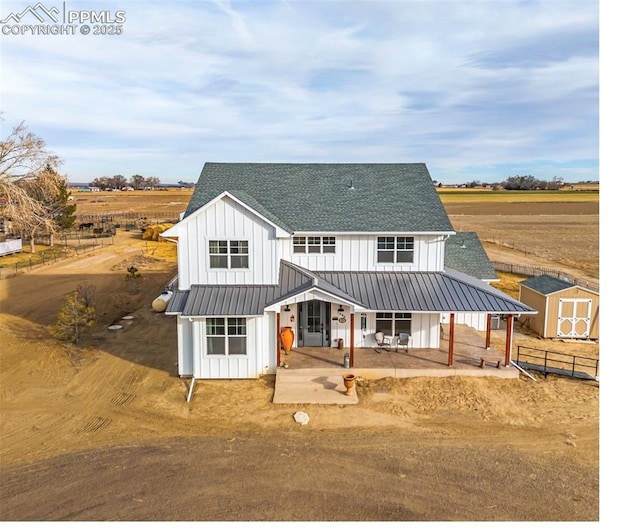 modern farmhouse style home with a shingled roof, a patio, an outbuilding, a shed, and board and batten siding