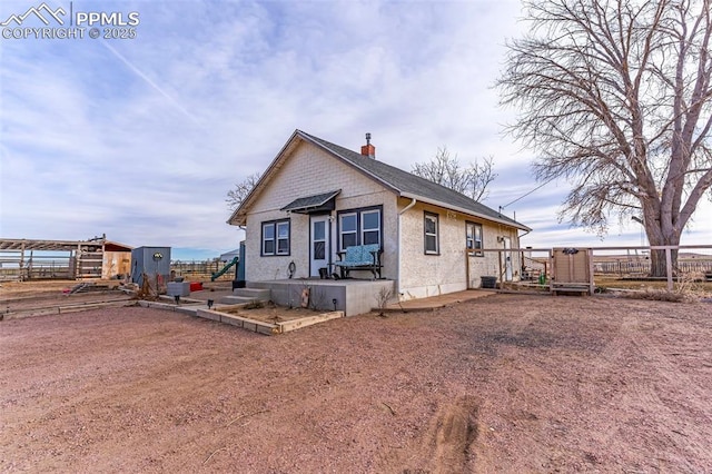 back of property with an outbuilding, fence, and a chimney