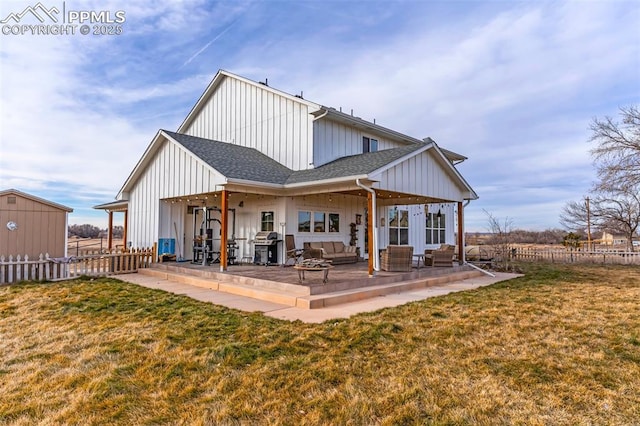 rear view of house with a patio, a shingled roof, fence, a yard, and board and batten siding