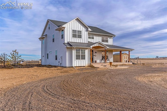 modern inspired farmhouse with metal roof, a storage shed, fence, board and batten siding, and a standing seam roof