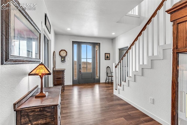 entrance foyer with stairs, baseboards, dark wood-style flooring, and a textured wall