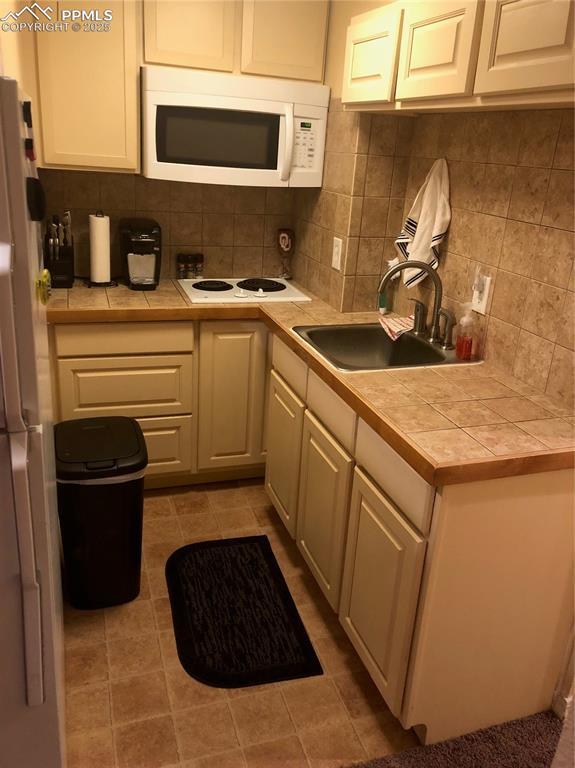 kitchen featuring tile counters, white appliances, a sink, and decorative backsplash