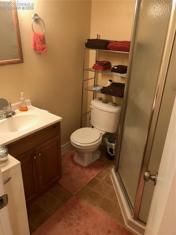 bathroom with a stall shower, tile patterned flooring, vanity, and toilet