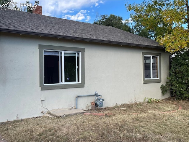 view of property exterior with stucco siding, a chimney, and roof with shingles