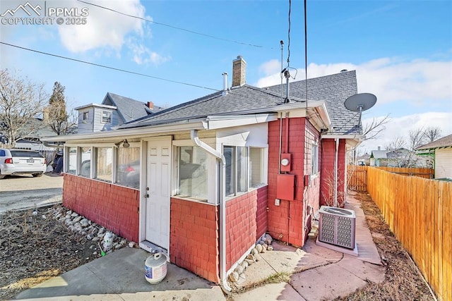 909 E 10th St, Pueblo, CO 81001 - view of home's exterior with central AC, fence, a chimney, and roof with shingles