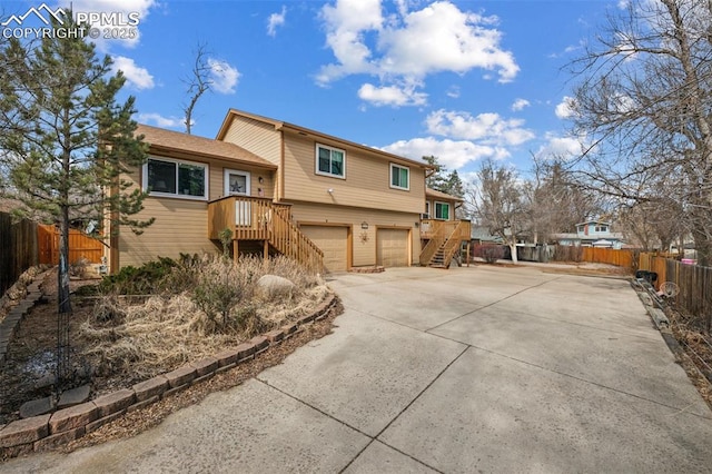 split level home featuring stairs, an attached garage, driveway, and fence