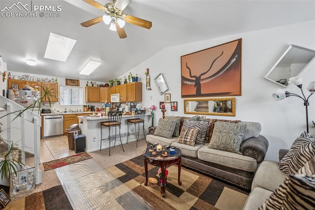 living area featuring vaulted ceiling with skylight, light colored carpet, and ceiling fan