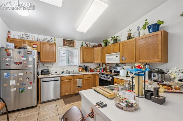 kitchen featuring a sink, appliances with stainless steel finishes, light tile patterned floors, and light countertops