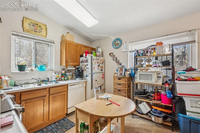 kitchen featuring white appliances, light countertops, lofted ceiling, and a sink