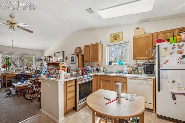 kitchen featuring white appliances, visible vents, a peninsula, a sink, and vaulted ceiling