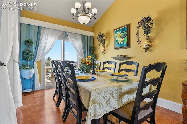 dining room featuring vaulted ceiling, a notable chandelier, wood finished floors, and baseboards