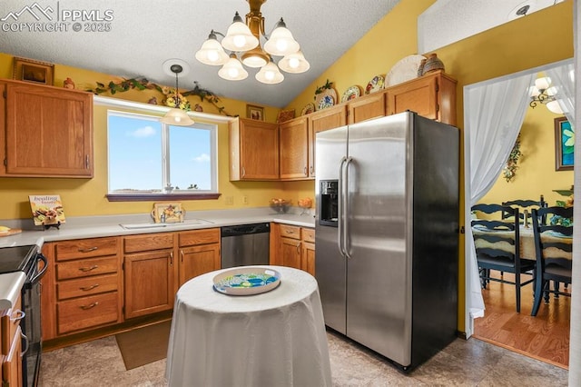 kitchen featuring light countertops, vaulted ceiling, appliances with stainless steel finishes, a textured ceiling, and a sink