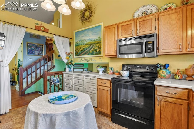 kitchen featuring stainless steel microwave, a chandelier, black electric range oven, and light countertops