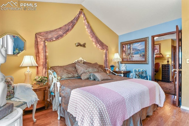 bedroom with lofted ceiling and wood finished floors