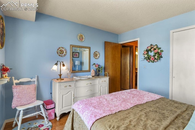 bedroom with wood finished floors and a textured ceiling