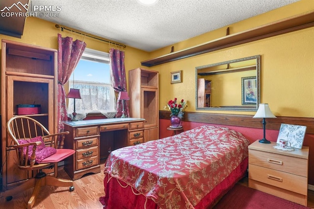 bedroom with a textured ceiling and wood finished floors