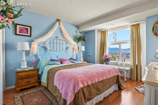 bedroom with a textured ceiling and wood finished floors