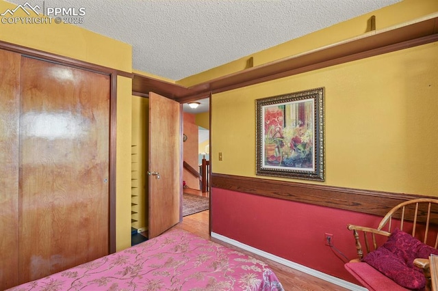 bedroom featuring baseboards, a textured ceiling, and wood finished floors